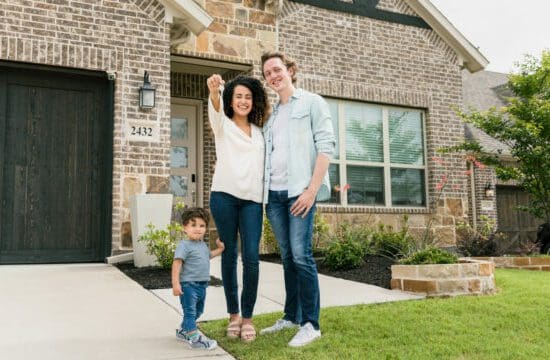 family in front of house with keys in hand