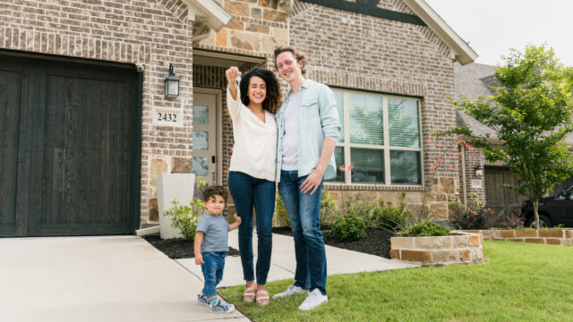 family in front of house with keys in hand