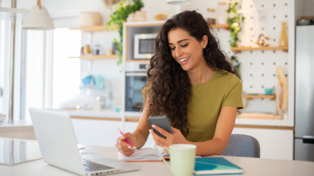 women with laptop looking at phone