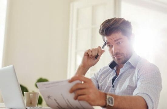 man with laptop looking at papers