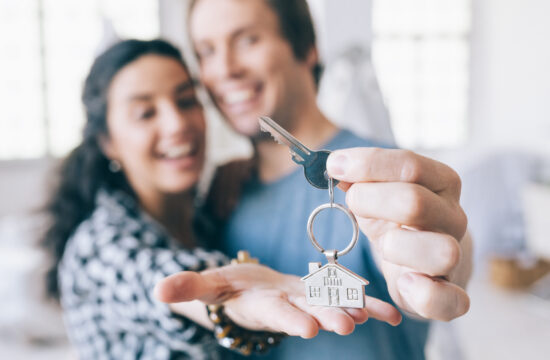 Couple cheerful home owners holding a key to their new home